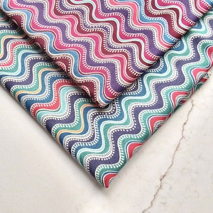 以下が含まれることがあります： 青、緑、赤、紫の色合いで波打つ模様が施された布地見本が3枚あります。