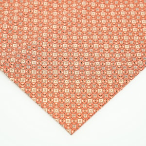 May include: A close-up of a fabric with a repeating pattern of orange and white circles with black outlines. The fabric has a subtle texture.