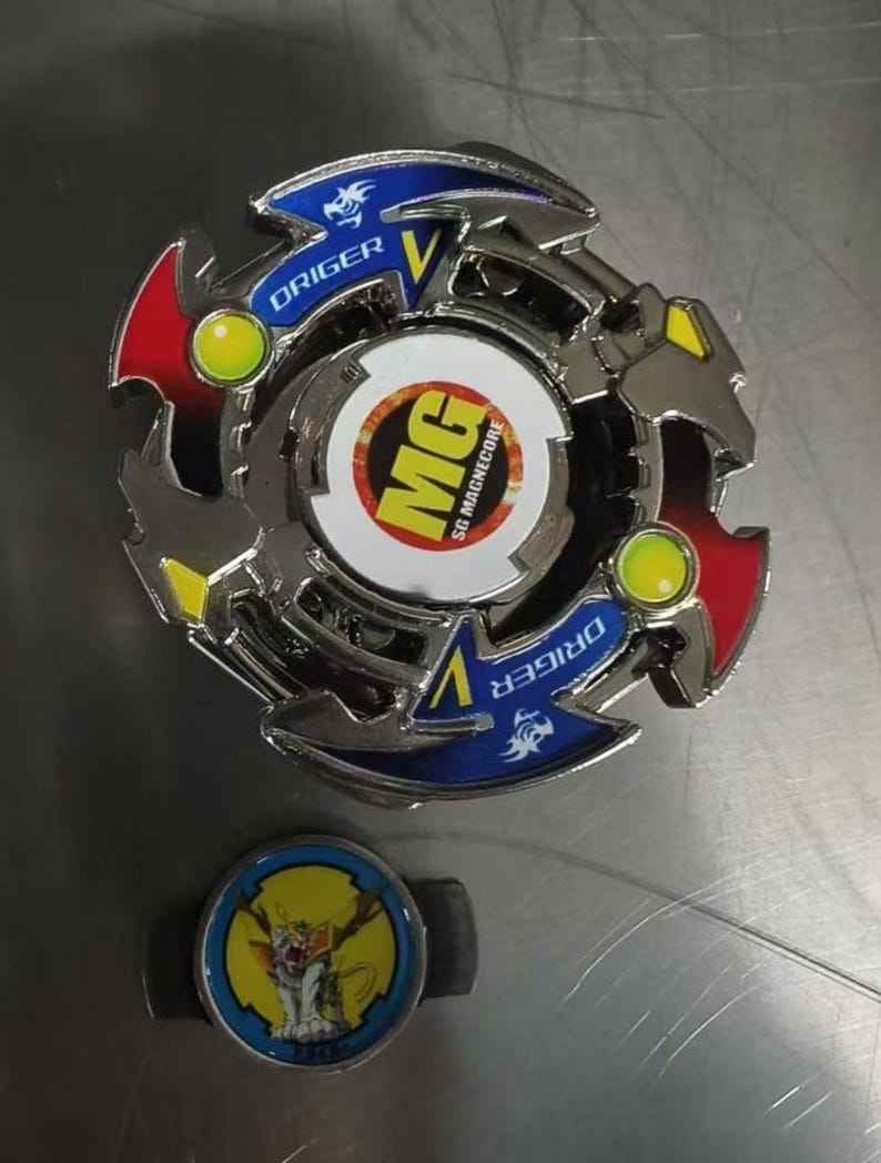 May include: A silver and multi-colored spinning top toy with the text "DRIGER" and "MG SG MAGNECORE". The toy has red, yellow, and blue accents. A smaller, matching piece with a cartoon graphic is also present.