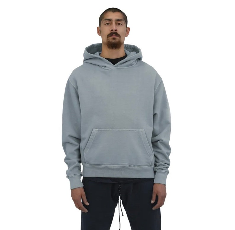 May include: A light blue hooded sweatshirt with a kangaroo pocket. The sweatshirt has a relaxed fit and a drawstring hood.