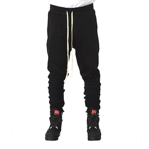 May include: Black sweatpants with a drawstring and a gathered look at the ankles. The sweatpants are worn with black boots.