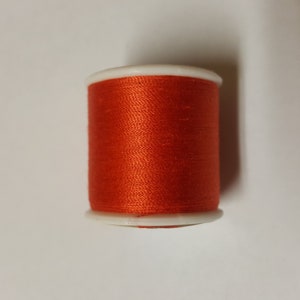 May include: A spool of bright orange thread.