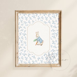 May include: A framed print of Peter Rabbit holding a carrot, surrounded by a blue and white floral pattern.