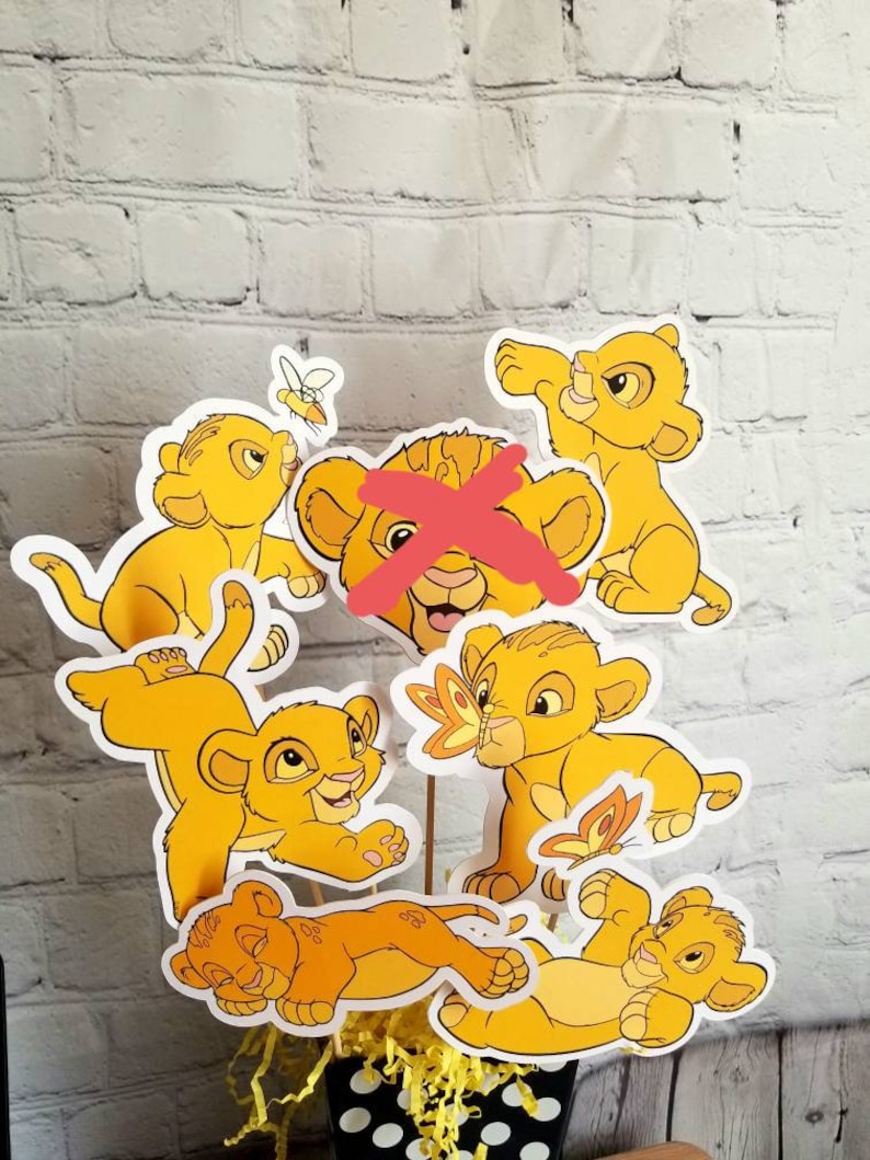 May include: A set of six yellow lion cub character cutouts, perfect for a party centerpiece or decoration. The lion cubs are in various poses, including sleeping, playing, and looking up.