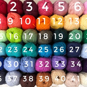 May include: A collection of 42 yarn balls in various colors, numbered 1 through 42. The colors include shades of red, pink, orange, yellow, green, blue, purple, brown, and cream. Each ball is tightly wound, suggesting they are for knitting or crochet projects.