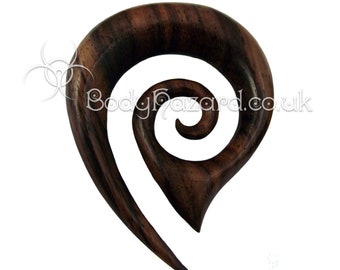 May include: A dark brown wooden spiral ear gauge with a unique design. The gauge is made of wood and has a natural finish.
