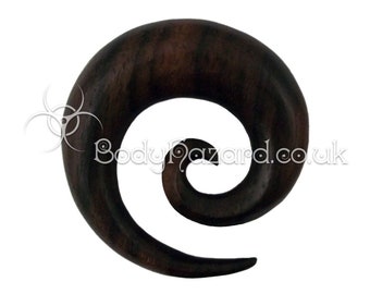 May include: A dark brown wooden spiral ear gauge. The gauge is made of wood and has a spiral design.
