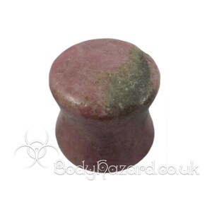 May include: A pair of pink and gray stone ear gauges. The gauges are flared and have a smooth, polished finish.