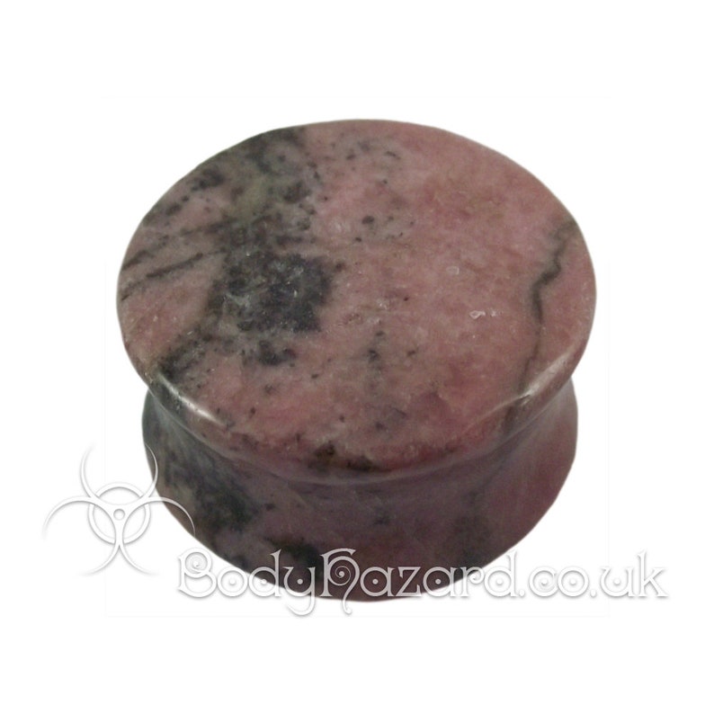 May include: A pink and black stone ear plug, also known as a flesh tunnel or gauge plug. The plug is made of a natural stone with a marbled pattern.