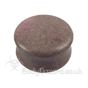 May include: A brown and gray stone ear plug. The ear plug is round and has a smooth surface.