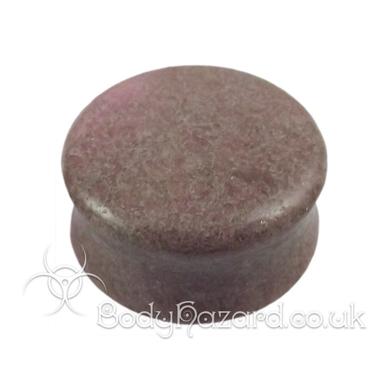 May include: A brown and gray stone ear plug. The ear plug is round and has a smooth surface.