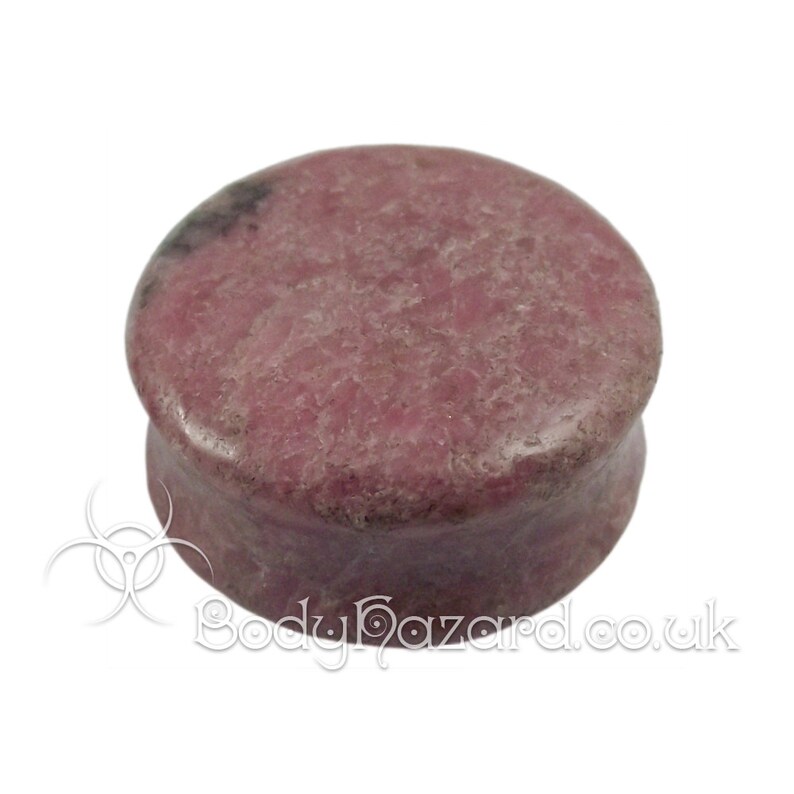 May include: A round, pink and gray stone plug for stretched earlobes. The plug is made of a natural stone with a mottled pattern.