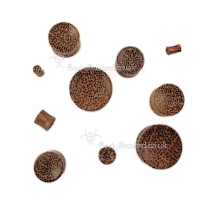 May include: Assortment of brown wood ear gauges with a speckled pattern. The gauges are various sizes and shapes.