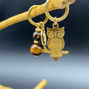 Könnte beinhalten: Goldener Eulenschmuck mit Tigeraugenperle an einem goldenen Ring.