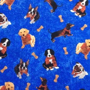 Puede incluir: Tela azul con un patrón repetido de perros con bufandas rojas y diseños en forma de hueso. Los perros son de varias razas, incluyendo un dachshund, un pug, un Boston terrier y un perro de montaña de Berna.