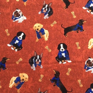 Puede incluir: Tela roja con un patrón repetido de perros con bufandas azules. Los perros son de diferentes razas, incluyendo un pug, un dachshund, un Boston terrier, un golden retriever y un perro de montaña de Berna. La tela está decorada con diseños en forma de hueso marrón.