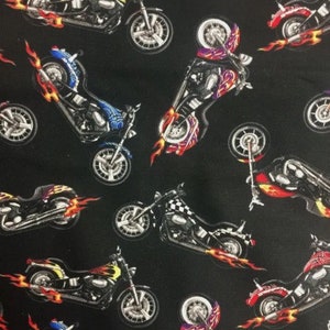 May include: A black fabric with a repeating pattern of colourful motorcycles with flames. The motorcycles are in various shades of blue, red, yellow, and purple.