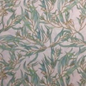 May include: White fabric with a repeating pattern of green and brown eucalyptus leaves. The fabric is measured with a ruler in inches.