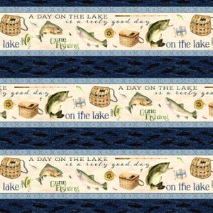 May include: Fishing-themed fabric with repeating patterns. The design includes illustrations of fish, fishing baskets, fishing reels, and the text "A Day on the Lake is a reely good day" and "Gone Fishing". The background is a light beige with dark blue stripes.