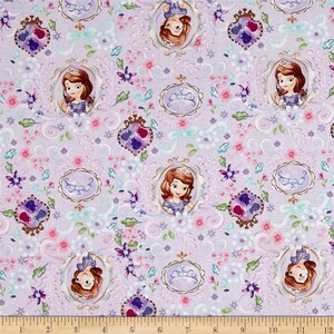 May include: Purple fabric with a repeating pattern of a cartoon princess in a gold frame, surrounded by flowers and swirls. The fabric has a light purple background with pink, white, and green accents.
