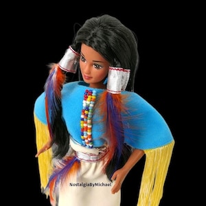 May include: A white ceramic mug with a black handle and the text "But First, Coffee" in a bold, black font. The mug is set against a blurred background, suggesting a cozy setting. The mug appears to be approximately 4 inches tall.