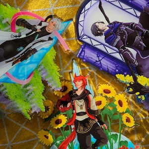 May include: Three anime-style character illustrations printed on clear acrylic. The first illustration features a character with white hair wearing a white coat and holding a sword. The second illustration features a character with black hair wearing a black and blue outfit. The third illustration features a character with red hair and a fox tail wearing a red and black outfit. The illustrations are surrounded by sunflowers and red flowers.