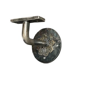 Puede incluir: Un soporte de barandilla de metal plateado con un diseño floral decorativo. El soporte tiene una base cuadrada y un brazo curvo.