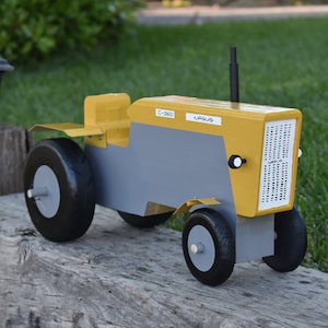 May include: A yellow and gray toy tractor with black wheels. The tractor has the text "C-360" and "URSUS" on the side.
