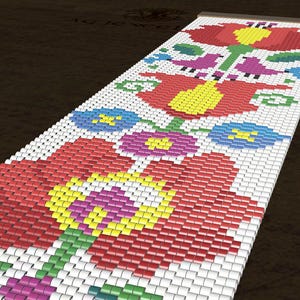 May include: A beaded bracelet with a floral design. The bracelet features red, yellow, blue, purple, and green flowers and birds on a white background. The bracelet is made of small, rectangular beads.