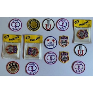 May include: A collection of circular and shield-shaped embroidered fabric patches featuring various designs, including text such as Sorry I Blew It, USA Screwing Team, and The Fucking Majority, with some patches still sealed in yellow and clear plastic packaging.