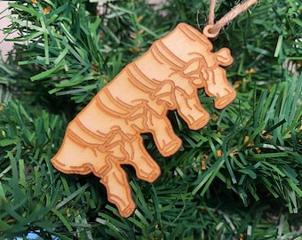 May include: A wooden Christmas tree decoration shaped like a human spine. The ornament is light brown and features a detailed design of the vertebrae.