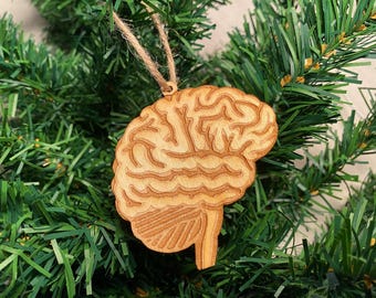 May include: A wooden brain ornament with a detailed design, hanging on a green artificial Christmas tree.