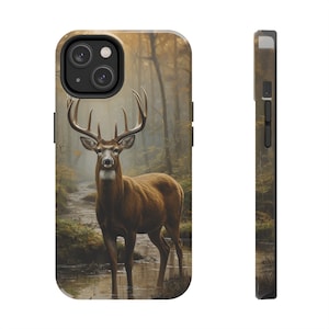 May include: A phone case with a brown and white deer standing in a forest with a stream. The deer has large antlers and is looking directly at the camera. The background is a blurry forest scene with trees and leaves.
