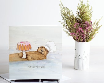 May include: A greeting card featuring a watercolor illustration of an otter wearing a chef's hat and holding a pink and orange cake. The card has the text "Otter-Lenghi" printed on it.