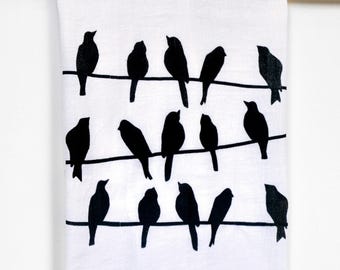 Paño de cocina con estampado de pájaros en un alambre.