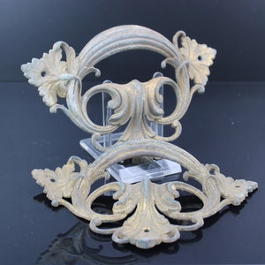 Puede incluir: Un par de tiradores de puerta de estilo antiguo adornados con un diseño floral decorativo. Los tiradores son de metal y tienen una pátina dorada y verde.