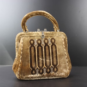 May include: A vintage handbag made of brown velvet with a geometric design. The bag has a top handle and a metal clasp.