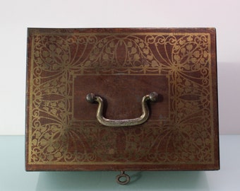 Art Nouveau gold colored top money safe box with key.