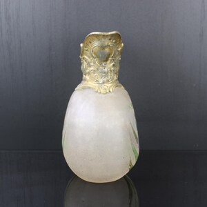 May include: A frosted glass vase with a gold-coloured metal top. The vase is shaped like an egg and has a delicate floral design.