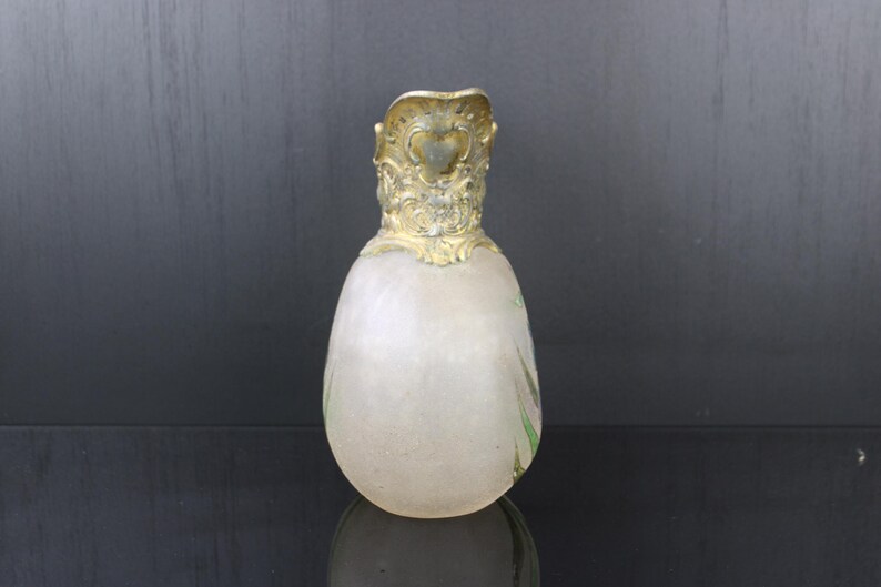 May include: A frosted glass vase with a gold-coloured metal top. The vase is shaped like an egg and has a delicate floral design.