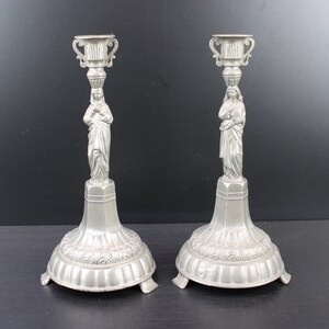 Antique pair of religious candle holders with man and woman.