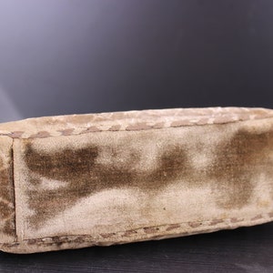 May include: A brown velvet handbag with a quilted design and a stitched edge.