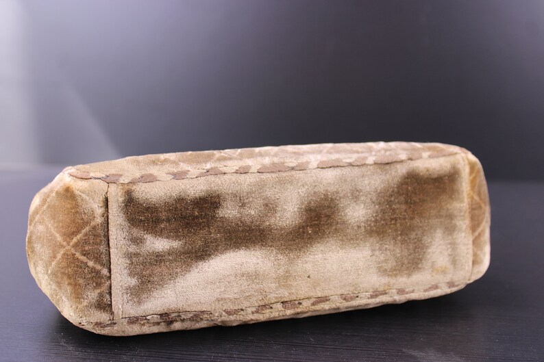 May include: A brown velvet handbag with a quilted design and a stitched edge.
