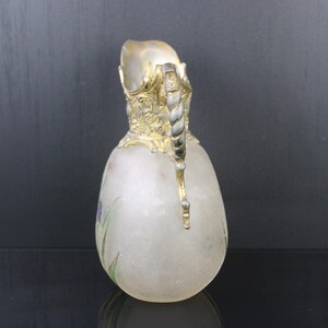 May include: A frosted glass jug with a gold and silver handle. The jug has a floral design painted on the side.