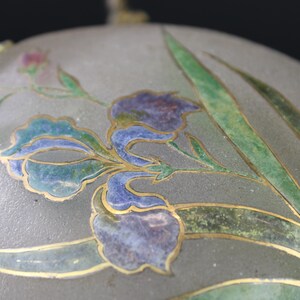 May include: A vintage glass bottle with a silver lid and a floral design. The bottle is decorated with a blue and green floral pattern, with gold accents.