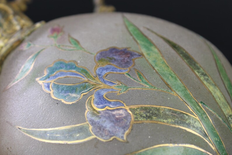 May include: A vintage glass bottle with a silver lid and a floral design. The bottle is decorated with a blue and green floral pattern, with gold accents.