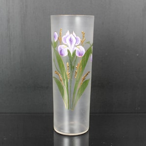 Pu&ograve; includere: Un vaso di vetro smerigliato con un motivo floreale dipinto a mano. Il design presenta fiori di iris viola con foglie verdi e dettagli dorati. Il vaso &egrave; cilindrico e misura circa 20 cm di altezza.