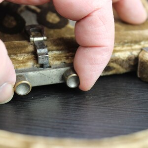 May include: Close-up of a vintage brown velvet purse with a metal clasp and two metal buttons. The purse is closed and the clasp is secured.
