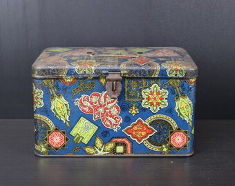 Könnte beinhalten: Eine vintage blaue Metalldose mit einem bunten Blumenmuster. Die Dose hat einen Klappdeckel mit einem Metallverschluss.