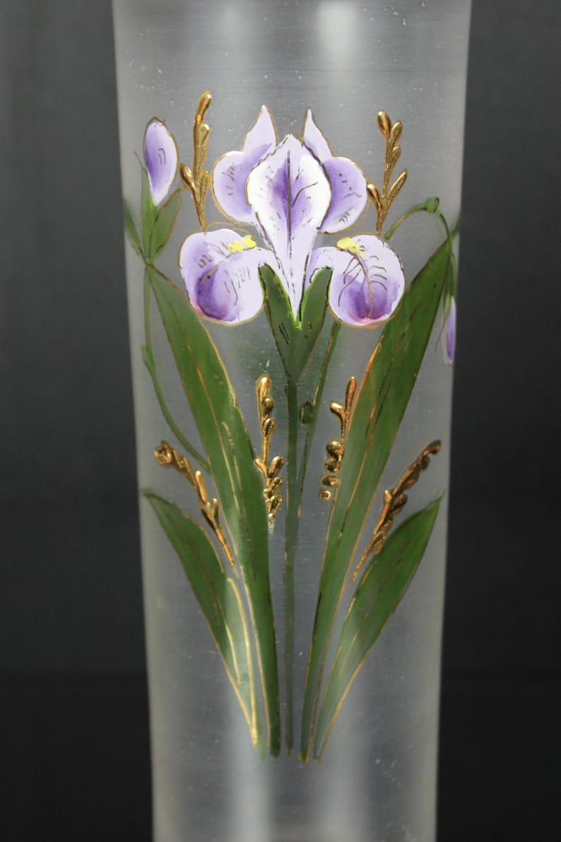 Pu&ograve; includere: Vaso in vetro smerigliato con un design di iris dipinto a mano. L'iris presenta petali viola, foglie verdi e dettagli dorati. Il vaso &egrave; cilindrico e ha una finitura liscia e smerigliata, creando un aspetto elegante.